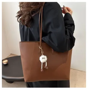 Vue détaillée du sac cabas en cuir PU marron porté épaule avec charm pelucheux mignon.