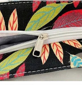 Close-up detail of smooth white zipper and botanical leaf print canvas fabric bag texture.