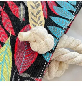 Canvas beach bag detail showing tropical leaf print and thick cotton rope handle knot.