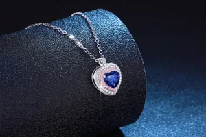 Gros plan detail du collier pendentif coeur avec pierre centrale bleue et pierres scintillantes.