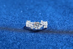 Close-up detail of silver moissanite ring with sparkly leaf design on blue background.