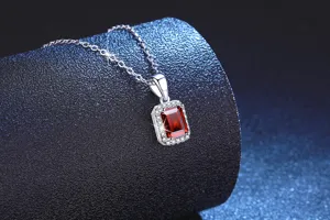 Detailed close-up shot of an elegant rectangular red gemstone pendant necklace on a dark stand.