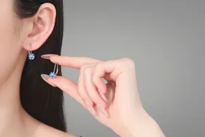 Gros plan de boucles d'oreilles en argent sterling et moissanite bleue, design élégant.