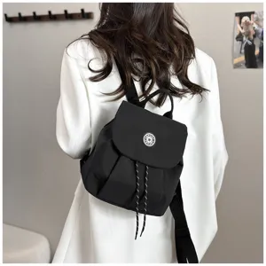 Vue détaillée d'un mini sac à dos noir porté au dos, avec rabat et fermeture à cordon.