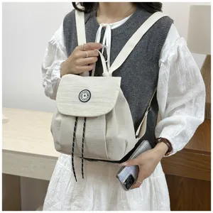 Vue détaillée du mini sac à dos décontracté beige, avec cordon de serrage et rabat.