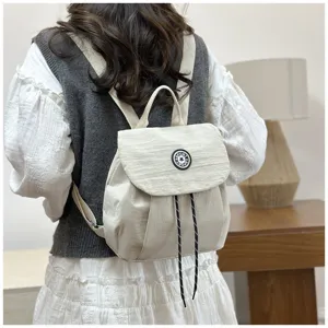 Vue détaillée d'un petit sac à dos décontracté pour femme en crème uni avec cordon.