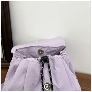 Gros plan sur les détails du sac à dos violet avec cordon de serrage et fermeture aimantée.
