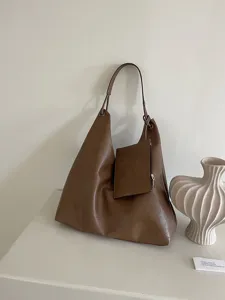 Close-up detail of the brown leather hobo shoulder bag highlighting its pouch and strap.