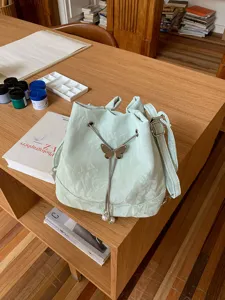 Mint green bucket bag detail, showcasing unique crinkle PU leather texture and butterfly.
