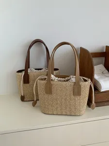 Woven straw bucket bag with leather handles and drawstring inner for summer vacation casual use.