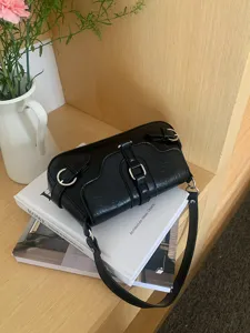 Black glossy faux leather underarm shoulder bag with edgy metal buckle straps for women.