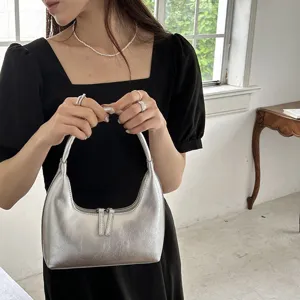 Primo piano della stylish borsa a mezzaluna metallica argentata con chiusura a zip.