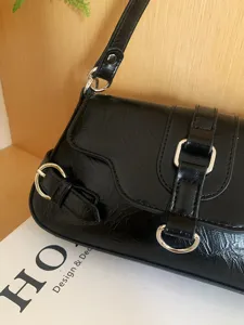 Black crinkled leather underarm bag detail showcasing stylish silver hardware and buckle strap.