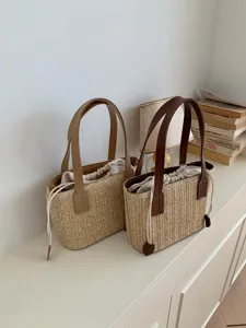Detailed view of woven straw bucket bag with contrast PU leather handles and drawstring lining.
