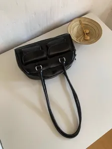 Detailed view of the stylish black glossy shoulder bag with dual handles and front pockets.