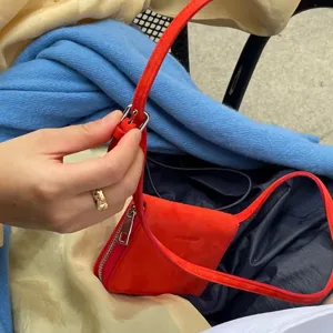 Detail view of the red suede mini crossbody bag strap adjustment and metal hardware.