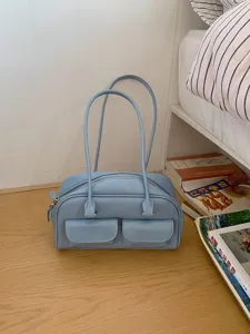 Trendy light blue patent leather shoulder bag with dual handles and stylish front pockets.