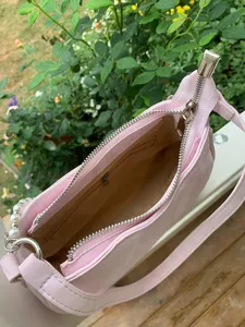 Pink baguette shoulder bag detail view featuring elegant pearl chain strap and secure metal zipper.