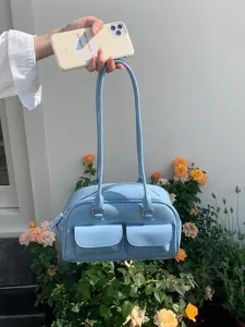 Detail view of a stylish light blue shoulder bag with dual handles and front pockets.