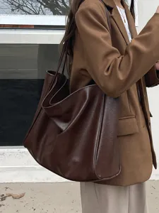 Close-up detail of the slouchy dark brown leather tote bag worn by model, soft texture.