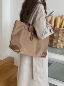 Detailed view of large capacity nylon tote bag with brown leather trim and shoulder straps.
