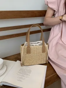 Detailed shot of straw woven bucket bag with brown handles and drawstring in scene.