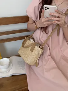 Straw bucket bag detail view, casual woven crossbody design with PU leather trim for summer beach.