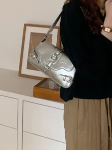 Silver metallic underarm shoulder bag with retro buckle straps, detailed fashion street style accessory.