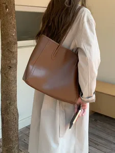 Detailed view of a brown leather tote bag, featuring large capacity and simple commute style.
