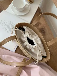 Detail view of woven straw bucket handbag with canvas drawstring lining and leather handles.