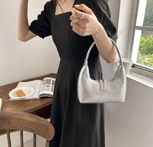 Dettaglio di una elegante borsa a spalla argentata a mezzaluna con finitura metallica.