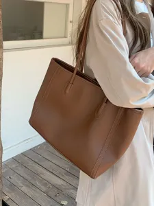 Detail view of a vintage brown leather tote bag worn by a model, showing large capacity.