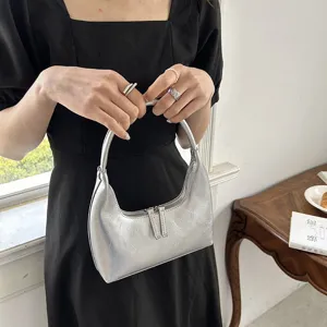 Dettaglio borsa a mezzaluna argentata, pelle lucida premium, elegante borsa francese chic.