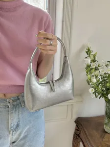 Dettaglio borsa a spalla mezzaluna argentata, elegante borsa hobo metallica per outfit estivi.