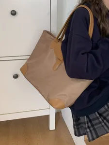 Detailed view of the khaki nylon tote bag featuring leather handles and flap closure.