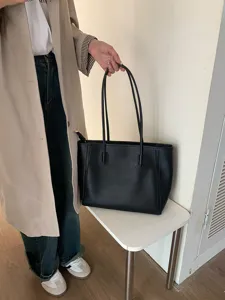 Detail view of the classic black leather tote bag, showing its large capacity and straps.