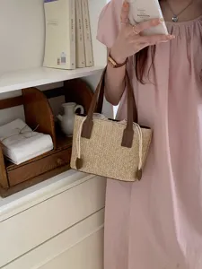 Detailed view of the stylish summer straw bucket handbag with brown leather handles and cute drawstrings.