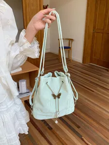 Mint green bucket bag detail, featuring delicate butterfly metal charm and pearl pendants for chic style.
