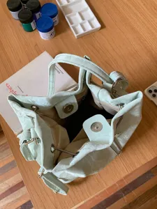 Mint green bucket bag detail showing interior lining, magnetic snap and adjustable drawstring.