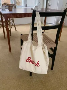 Gedetailleerd overzicht van de casual canvas schoudertas met stijlvolle rode Beach opdruk.