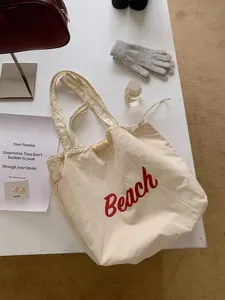 Detail van de beige casual tote tas met rode strandletterprint en een handig koordsluiting.