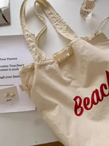 Gedetailleerd overzicht van canvas tote bag, beige schoudertas met rode letterprint opdruk.