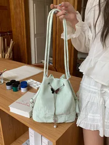 Mint green fashion bucket bag detail showing butterfly metal hardware and stylish pearl decor.