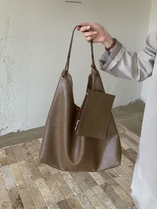 Close-up detail of stylish brown tote shoulder bag with pouch, casual large capacity design.