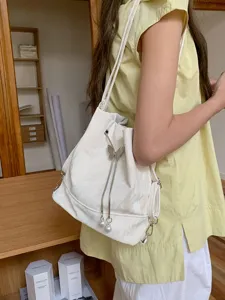 White stylish bucket shoulder bag with butterfly pearl drawstring detail, trendy design.