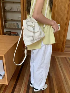 White drawstring bucket bag for women, versatile shoulder backpack with metal and pearl decor.