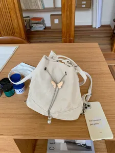 White PU leather bucket bag for women, Korean style chic backpack with butterfly and pearl charm.