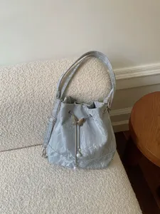 Silver crinkled bucket bag featuring a metal butterfly pearl pendant and adjustable strap.