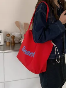Gedetailleerd opname van een rode canvas shopper met blauwe Beach letterprint en aantrekkoord.