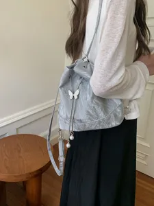 Stylish light blue bucket backpack with cute butterfly and pearl pendant for women daily use.